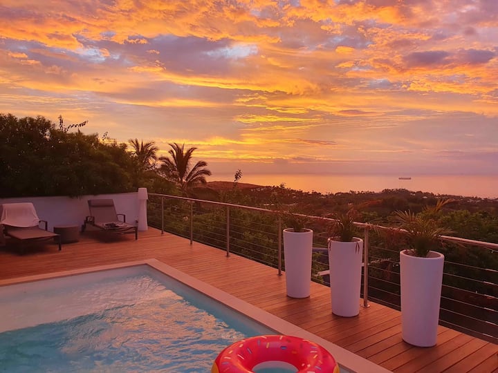 Piscine et océan sous un ciel orangé au coucher du soleil